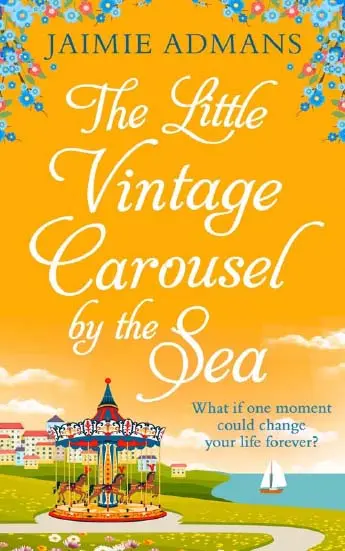 A carousel by the sea set in front of a small town